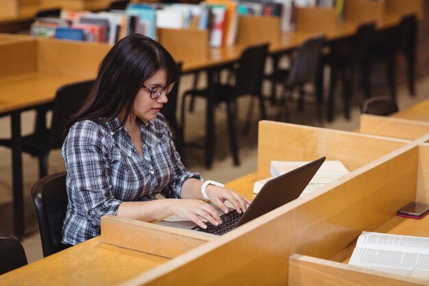 Studentin mit Laptop in Bibliothek