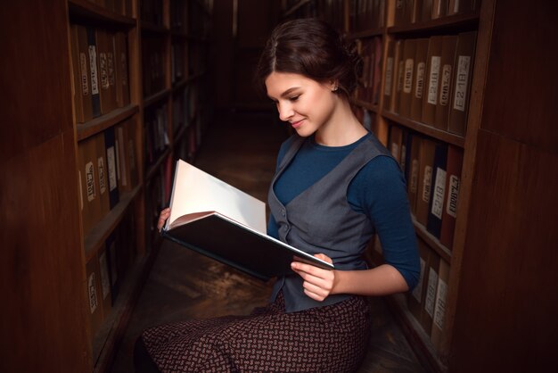 Studentin mit offenem Buch in der Universitätsbibliothek.