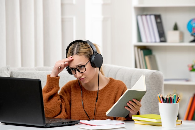 Studentin online süßes Mädchen mit Brille und Pullover, das am Computer studiert und die Stirn hält