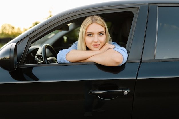 Studentin posiert im Auto, Unterricht in der Fahrschule. Mann, der Dame lehrt, Fahrzeug zu fahren.