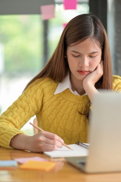 Studentinnen im Teenageralter lernen und machen sich Notizen durch Videokonferenzen.