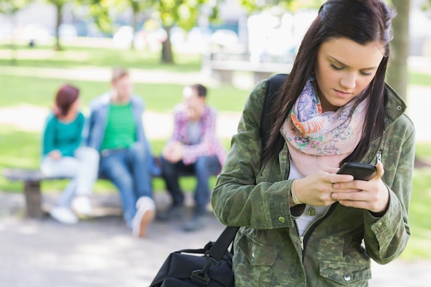 Studentinversenden von sms mit unscharfen Studenten im Park