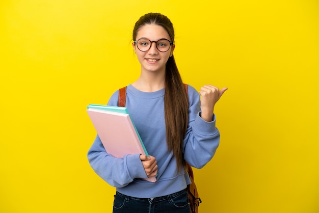 Studentische Kinderfrau über isolierter gelber Wand, die auf die Seite zeigt, um ein Produkt zu präsentieren