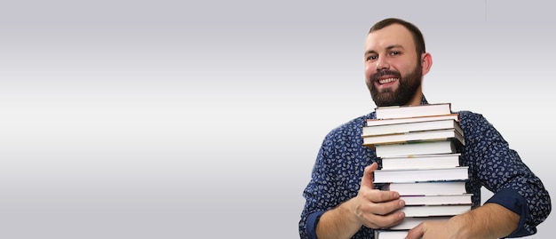 Studentischer erwachsener Bartmann mit Buchstapel in einer Bibliothek