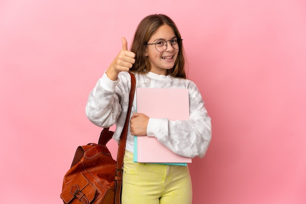 Studentisches kleines Mädchen über isoliertem rosa Hintergrund mit Daumen hoch, weil etwas Gutes passiert ist