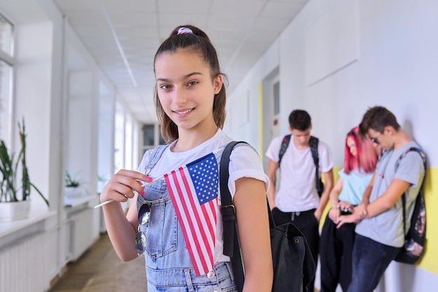 Studentisches Teenager-Mädchen mit USA-Flagge im Hintergrund der Schulkindergruppe