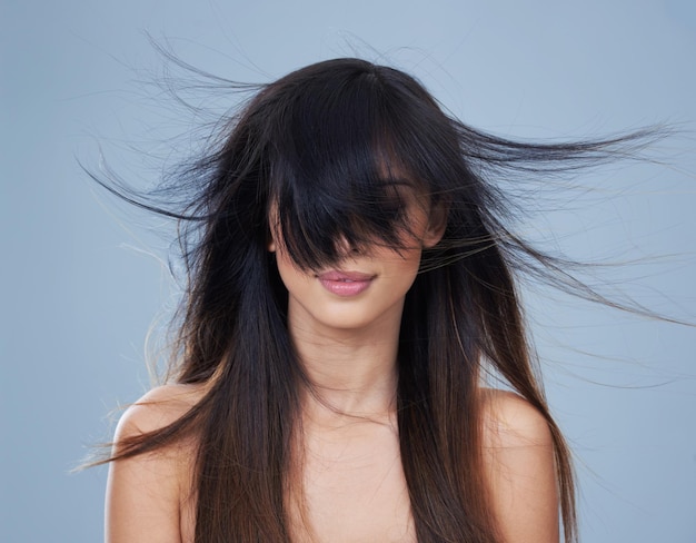 Studio-Modell und Wind mit langen Haaren in den Augen mock up und Keratin-Behandlung für Glanz oder Salon Ergebnis arabische Frau Schönheit oder entspannen Sie sich mit Conditioner für Haarpflege Gesundheit oder Shampoo mit blauem Hintergrund