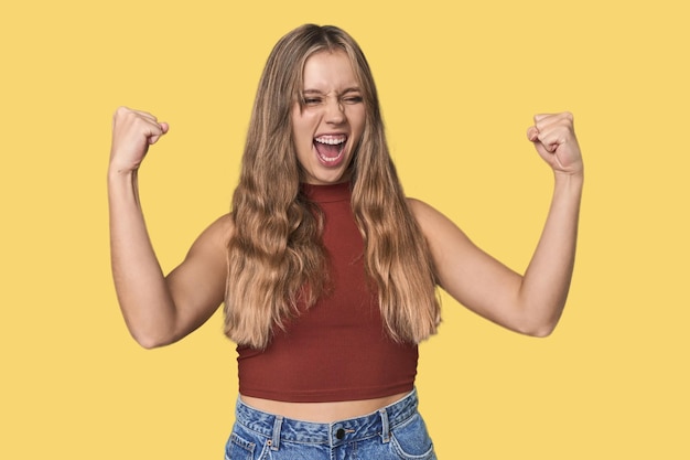 Foto studio-porträt einer blonden kaukasischen frau, die nach einem sieg-sieger-konzept die faust hebt