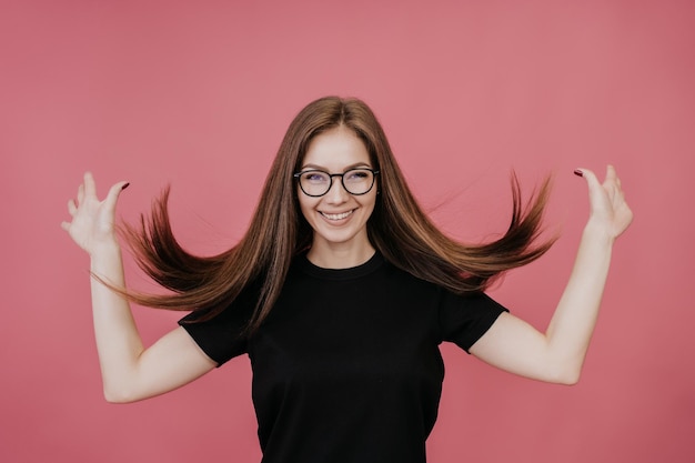 Studio-Shooting einer Italienerin in einem schwarzen T-Shirt mit Brille und flatternden langen, lockeren Haaren in der Luft