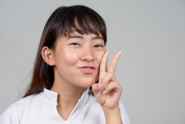 Studioaufnahme der jungen asiatischen Frau gegen weißen Hintergrund