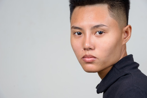 Studioaufnahme der jungen asiatischen Lesbenfrau mit kurzen Haaren gegen weißen Hintergrund