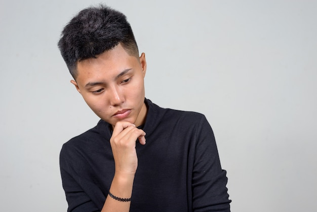 Studioaufnahme der jungen asiatischen Lesbenfrau mit kurzen Haaren gegen weißen Hintergrund