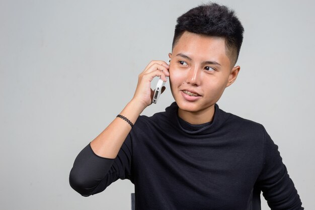 Studioaufnahme der jungen asiatischen Lesbenfrau mit kurzen Haaren vor weißem Hintergrund