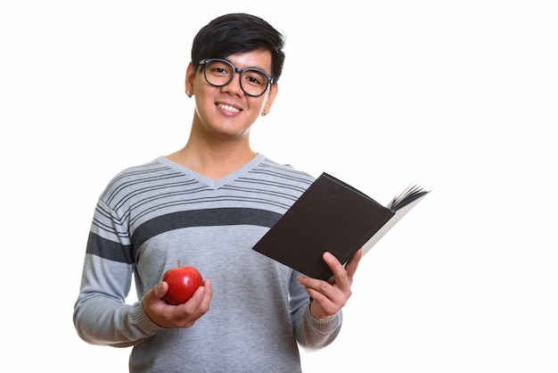 Studioaufnahme des glücklichen asiatischen Mannes lächelnd, der Buch und rote Appl hält