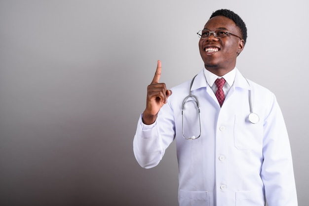 Studioaufnahme des jungen afrikanischen Mannarztes, der Brillen gegen weißen Hintergrund trägt