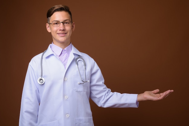 Studioaufnahme des jungen gutaussehenden Arztes gegen braunen Hintergrund