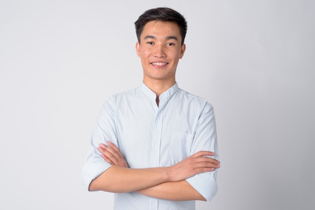 Studioaufnahme des jungen schönen asiatischen Geschäftsmannes gegen weißen Hintergrund