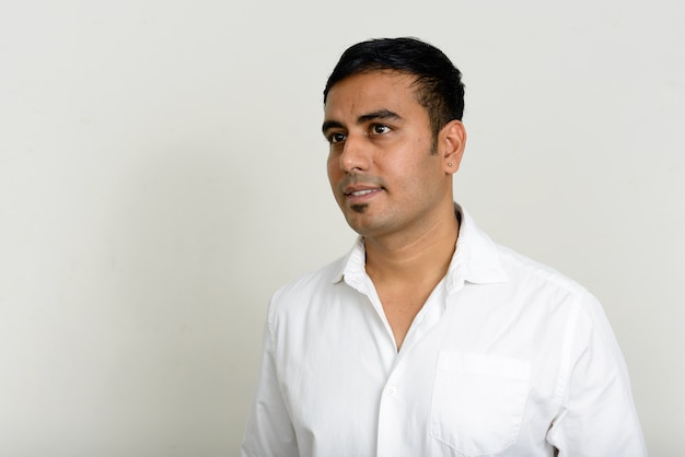 Studioaufnahme des schönen indischen Geschäftsmannes gegen weißen Hintergrund
