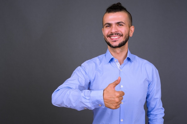 Studioaufnahme des schönen türkischen Geschäftsmannes gegen grauen Hintergrund