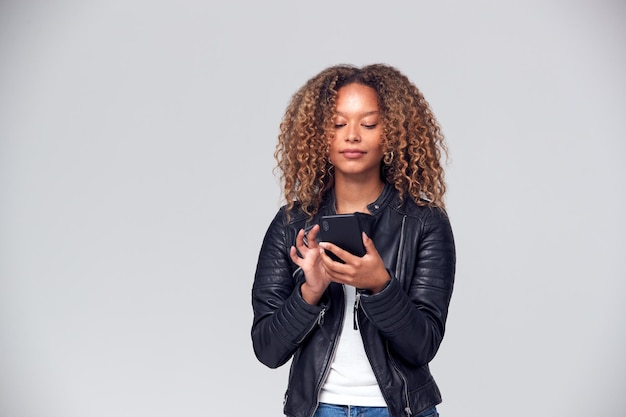 Studioaufnahme einer Frau in Lederjacke mit Handy