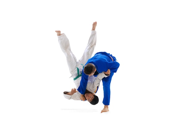 Studioaufnahme von zwei Männern, die professionelle Judo-Athleten trainieren, isoliert auf weißem Hintergrund