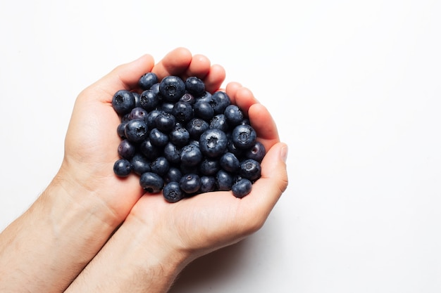 Studiobild von frischen Blaubeeren in männlichen Händen, isoliert auf weiss.