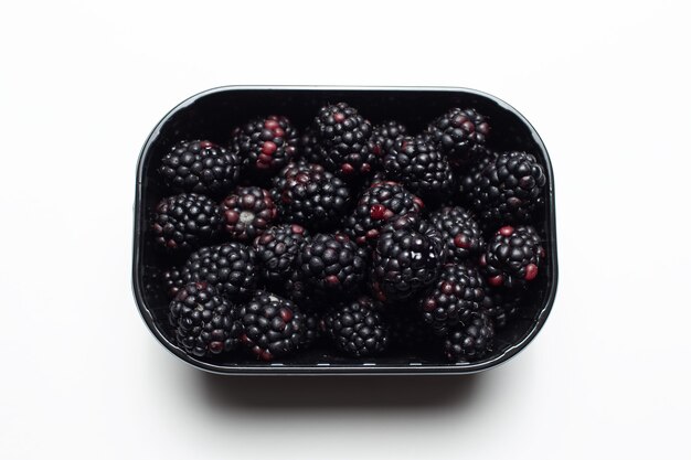 Studiofotografie einer Plastikbox voller Brombeeren, isoliert auf weiss.