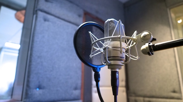 Studiomikrofon mit Shock Mount und Poppfilter auf professionellem Stativ im Akustikschaumraum