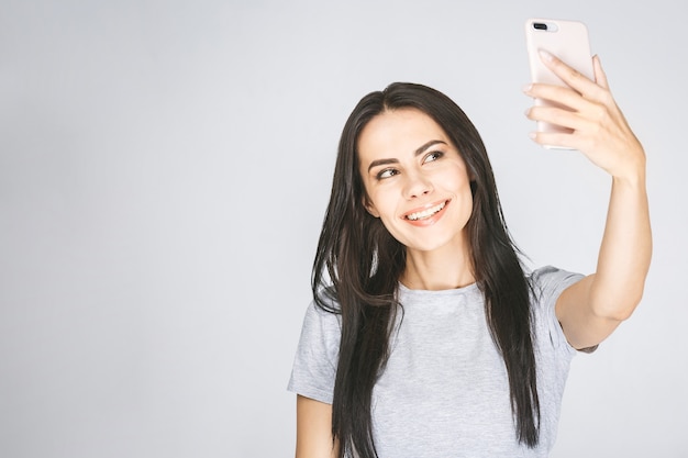 Studioporträt der schönen Frau, die mit weißen Zähnen lächelt und selfie macht, sich fotografierend