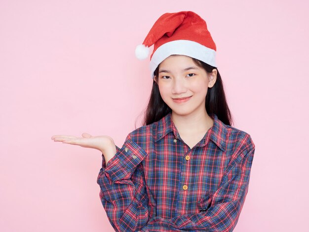 Studioporträt des jungen Mädchens, das Weihnachtsmütze auf rosa Hintergrund trägt. Weihnachtskonzept.