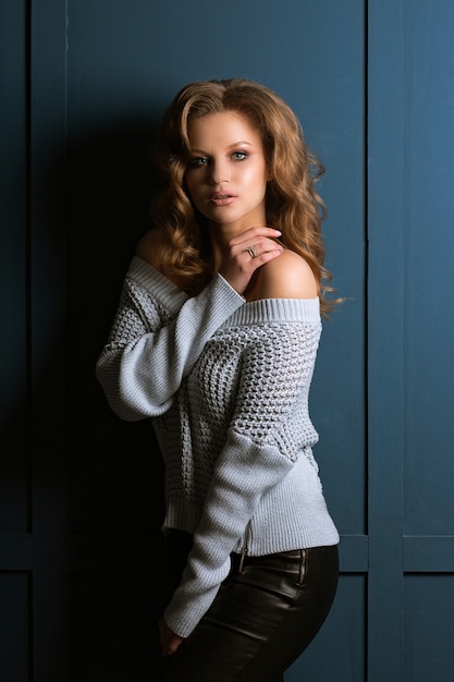 Studioporträt des schönen blonden Modells mit Mode-Make-up trägt Strickpullover