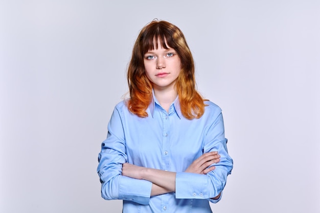 Studioporträt einer ernsten traurigen jungen Frau, die auf hellem Hintergrund in die Kamera blickt