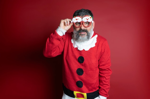 Studioporträt eines bärtigen Mannes im engen Weihnachtsmannhut und in den Weihnachtskleidern