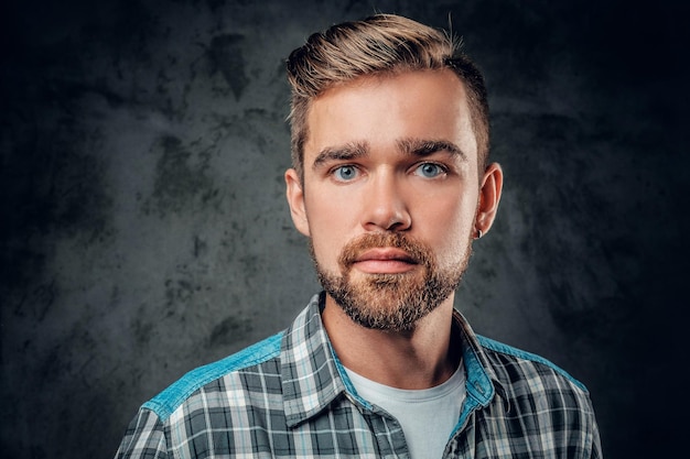 Studioporträt eines blauäugigen, bärtigen Hipster-Männchens auf grauem Hintergrund.