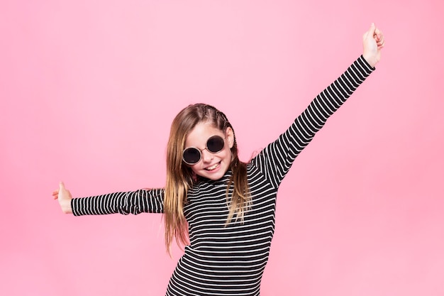 Studioporträt eines hübschen Mädchens mit Sonnenbrille vor rosa Hintergrund