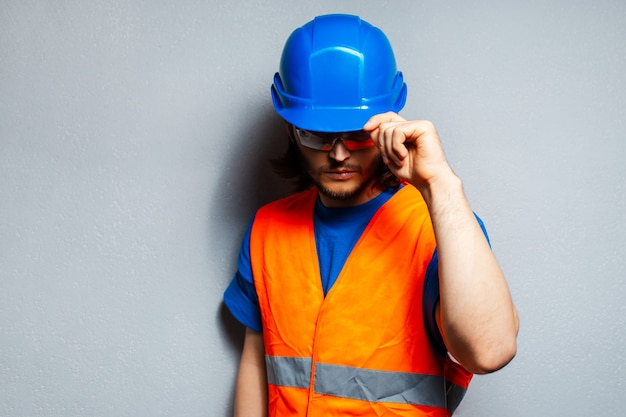 Foto studioporträt eines jungen bauarbeiters, der sicherheitsausrüstung trägt;