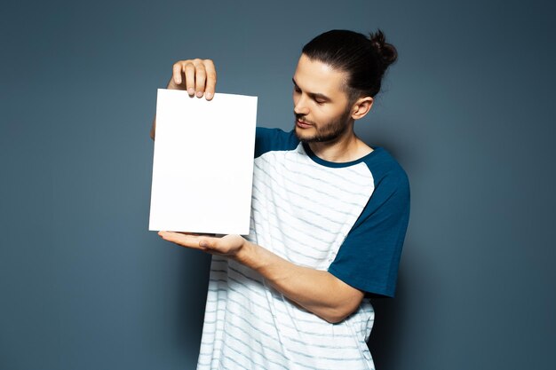 Studioporträt eines Mannes, der weiße leere Papptafel auf blauem Hintergrund hält