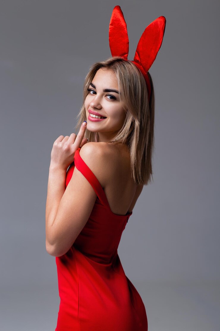 Studioporträt eines schönen lächelnden Mädchens in einem roten Kleid und mit Hasenohren