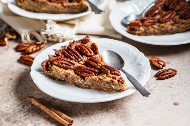 Stück der Pekannuss-Torte auf grau-braunem Hintergrund. Veganes Dessertkonzept.