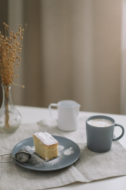 Stück frischer hausgemachter Kuchen mit Tasse Cappuccino auf einem Tisch