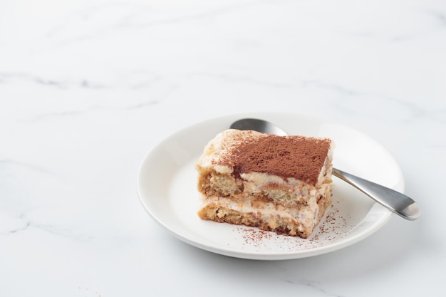 Stück hausgemachter Tiramisu-Kuchen-Dessert auf weißem Marmorhintergrund