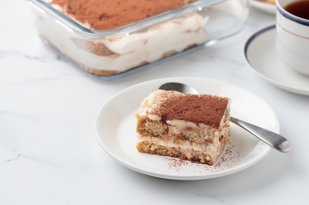 Stück hausgemachter Tiramisu-Kuchen-Dessert auf weißem Marmorhintergrund