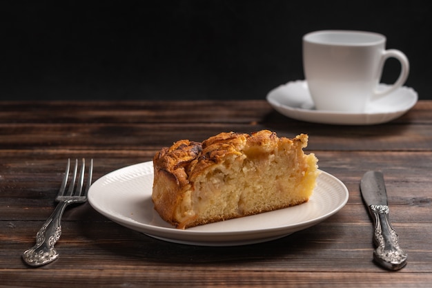 Stück hausgemachter traditioneller kornischer Apfelkuchen auf einem weißen Teller auf dem bewaldeten Tisch selektiver Fokus