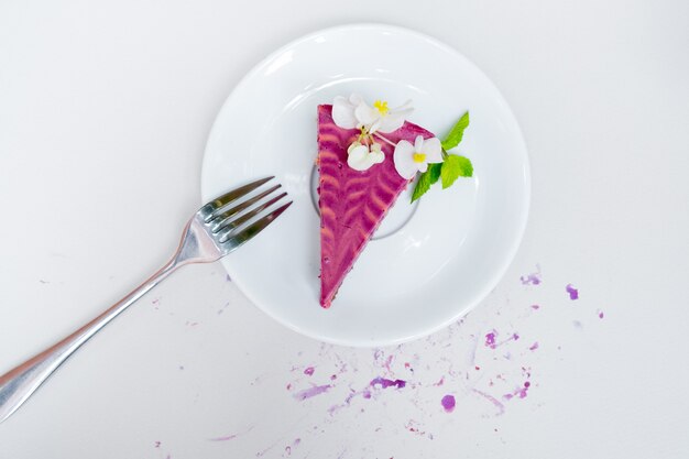 Stück Käsekuchen mit Blaubeeren auf einem weißen Teller auf weißem Hintergrund. . Sicht von oben.