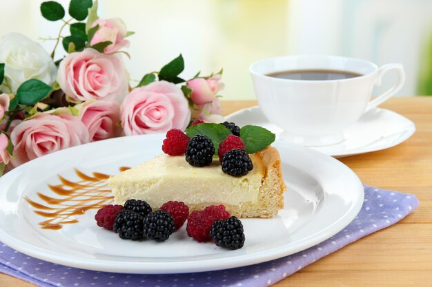 Stück Käsekuchen mit Himbeere und Brombeere auf Teller auf hellem Hintergrund