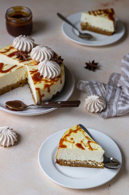 Stück Karotten-Vanille-Käsekuchen mit gesalzenem Karamell-Topping und Baiser auf einer weißen Keramikplatte