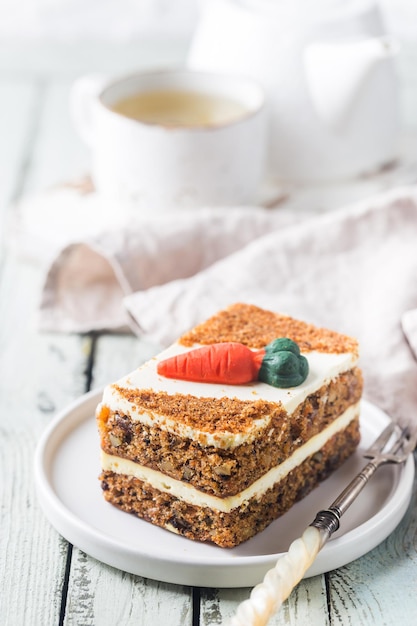 Stück Karottenkuchen mit Frischkäse-Zuckerguss auf Holztisch