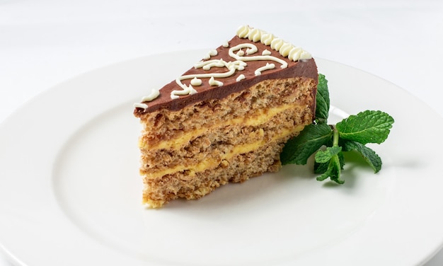 Stück Kiew, Kiewer Kuchen mit Schokoladencreme und dekorierter Minze auf weißem Teller