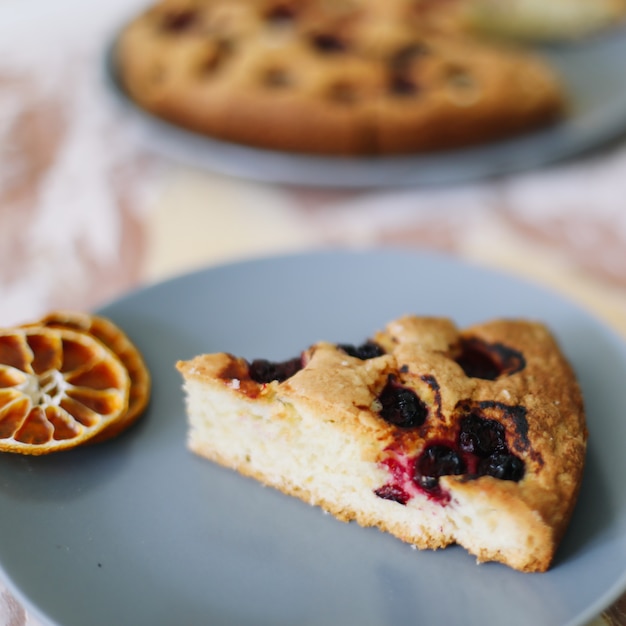 Stück Kuchen auf Teller mit Tasse Tee auf weißem Tisch