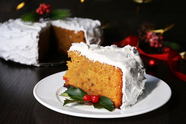 Stück Kuchen bedeckt Sahne mit Weihnachtsdekoration auf Holztisch